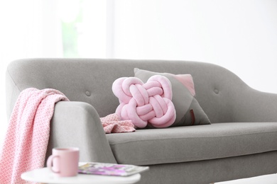 Pillows and plaid on sofa indoors. Unusual cushion design