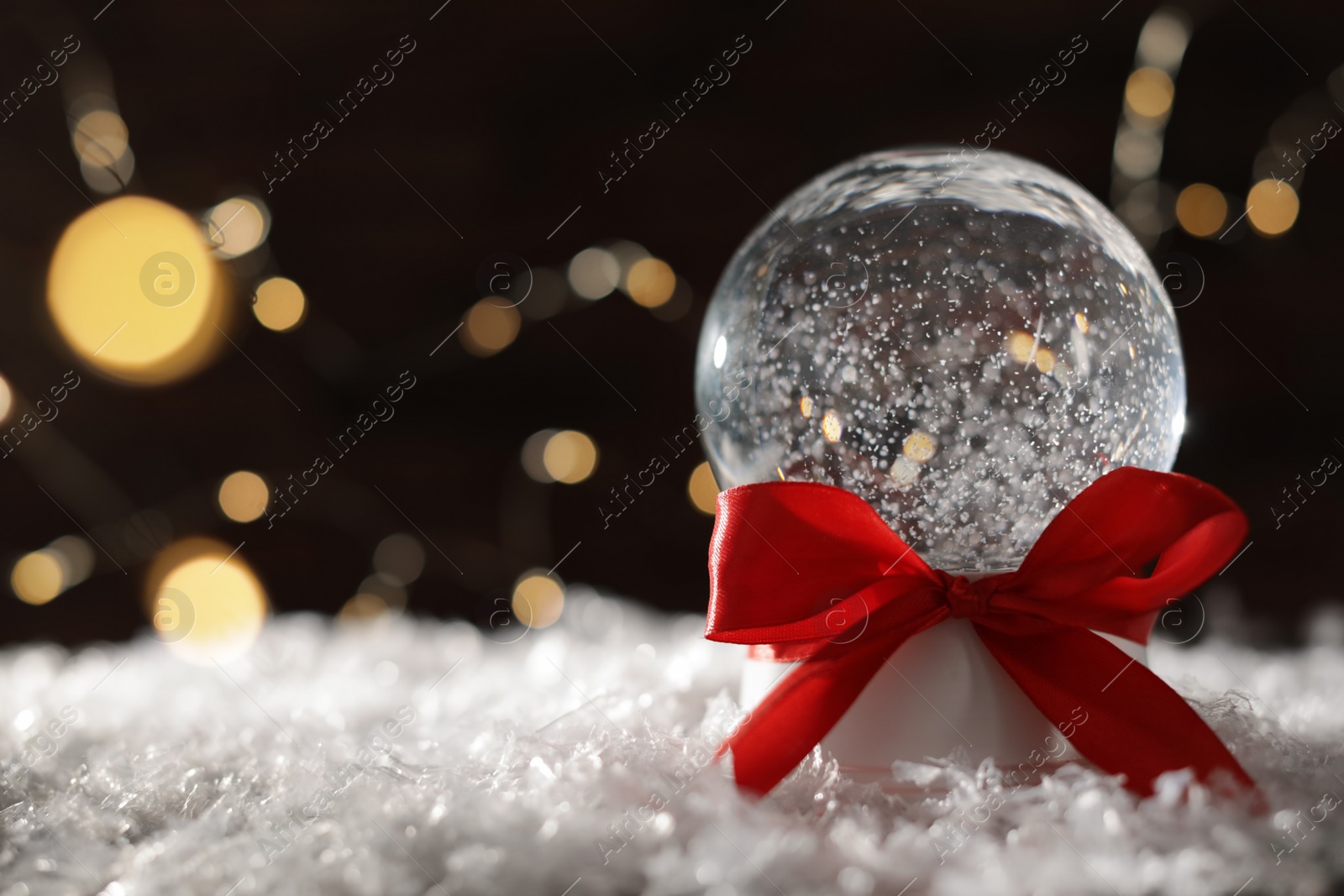 Photo of Christmas glass globe with artificial snow on blurred background. Space for text