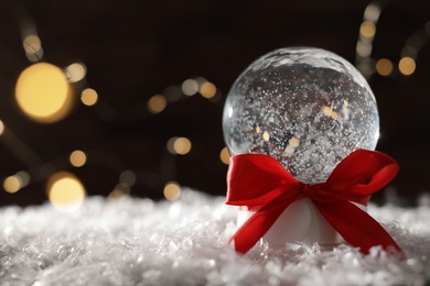 Christmas glass globe with artificial snow on blurred background. Space for text