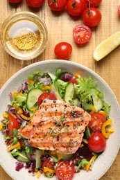 Photo of Bowl with tasty salmon and mixed vegetables on wooden table, flat lay