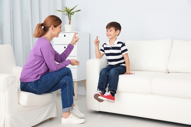 Photo of Hearing impaired mother and her child talking with help of sign language indoors