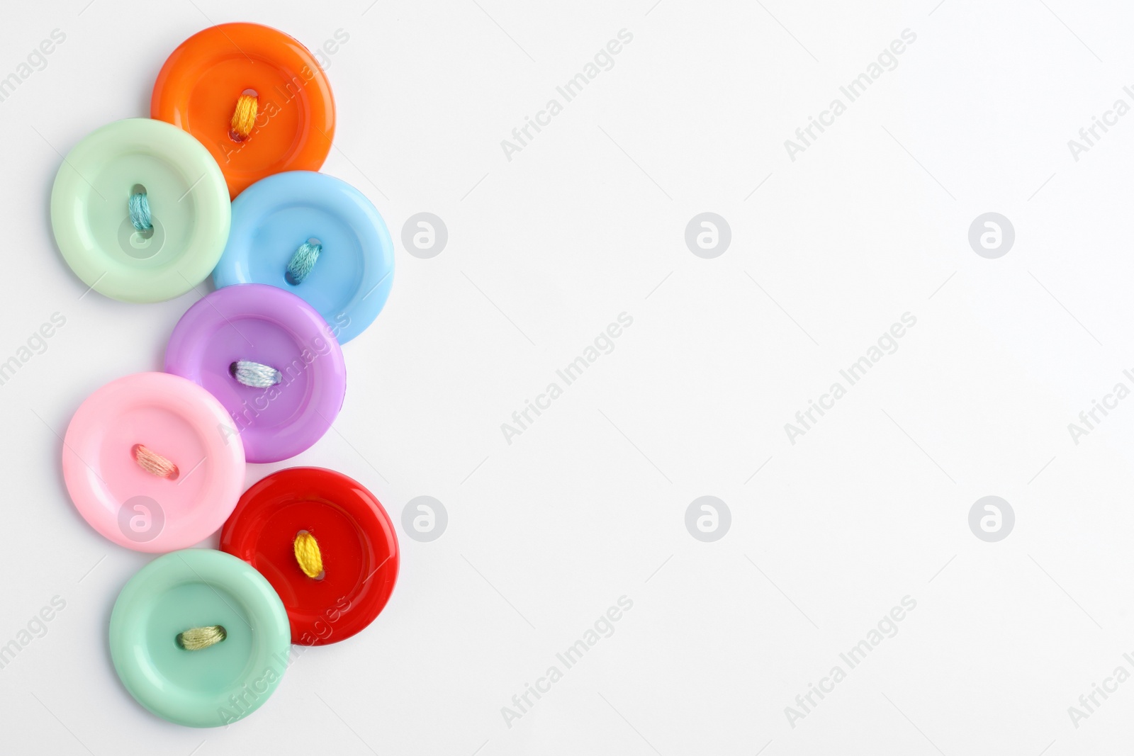 Photo of Many colorful sewing buttons on white background, top view