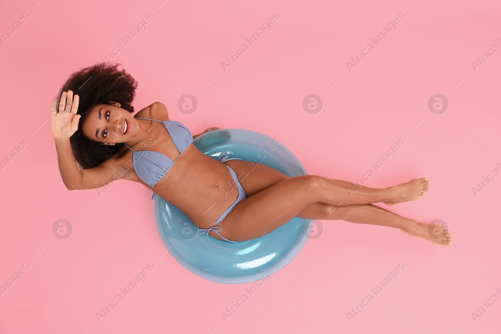 Photo of Beautiful woman in stylish bikini with inflatable ring on pink background, top view