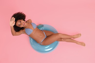 Photo of Beautiful woman in stylish bikini with inflatable ring on pink background, top view