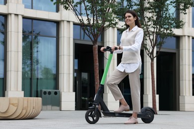Photo of Businesswoman with modern electric kick scooter on city street