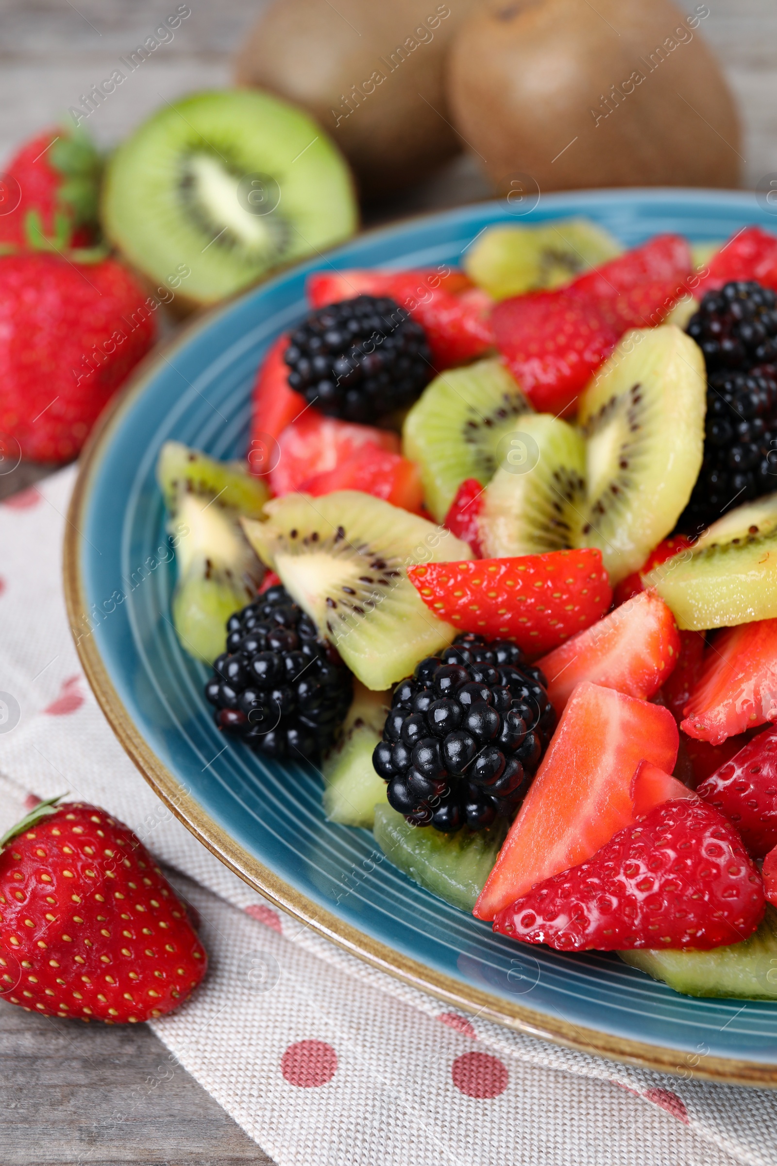 Photo of Plate of delicious fresh fruit salad on table, closeup