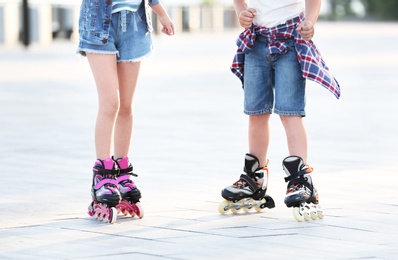 Photo of Little children roller skating on city street, closeup view