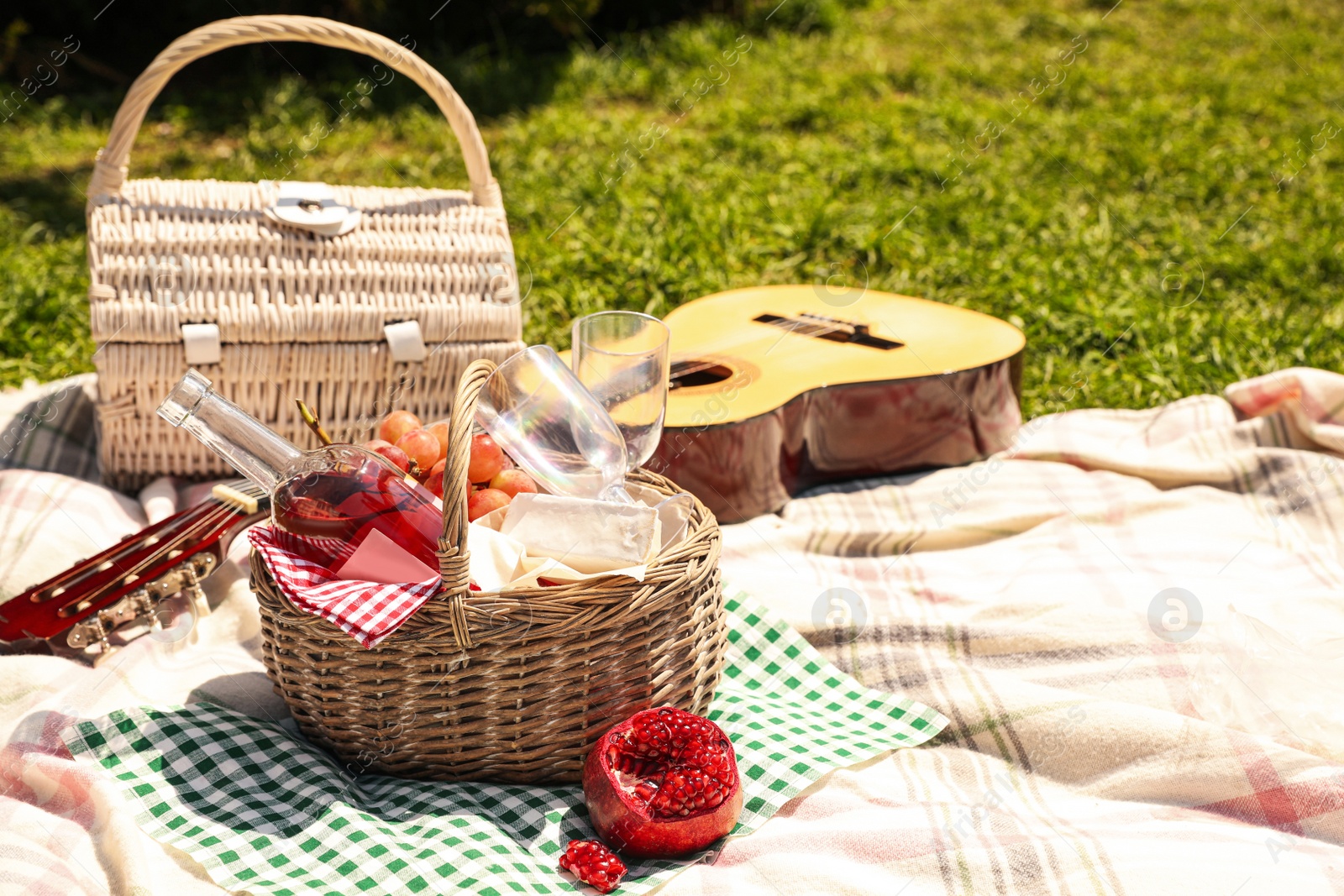Photo of Delicious food and wine in picnic basket on blanket outdoors. Space for text