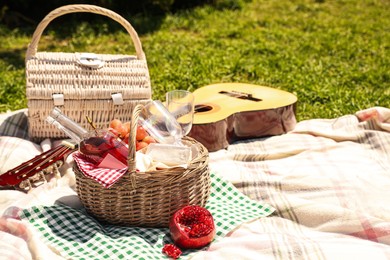 Photo of Delicious food and wine in picnic basket on blanket outdoors. Space for text