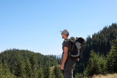 Tourist with backpack in mountains on sunny day. Space for text