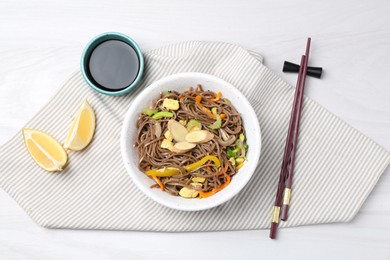 Photo of Stir-fry. Delicious cooked noodles with chicken and vegetables in bowl served on light wooden table, flat lay