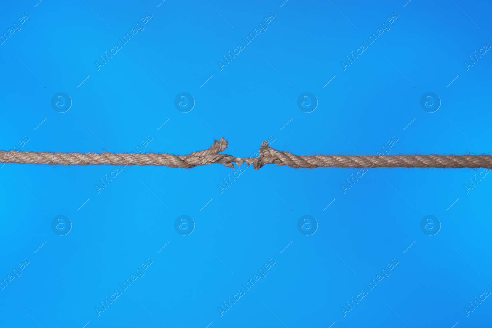 Photo of Stretched frayed rope breaking on color background