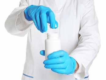 Photo of Doctor in medical gloves opening bottle of pills on white background