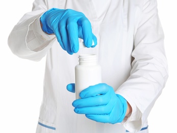 Doctor in medical gloves opening bottle of pills on white background