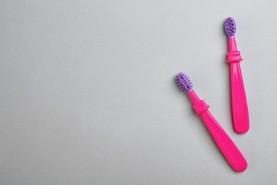 Photo of Manual toothbrushes for children on gray background, top view with space for text