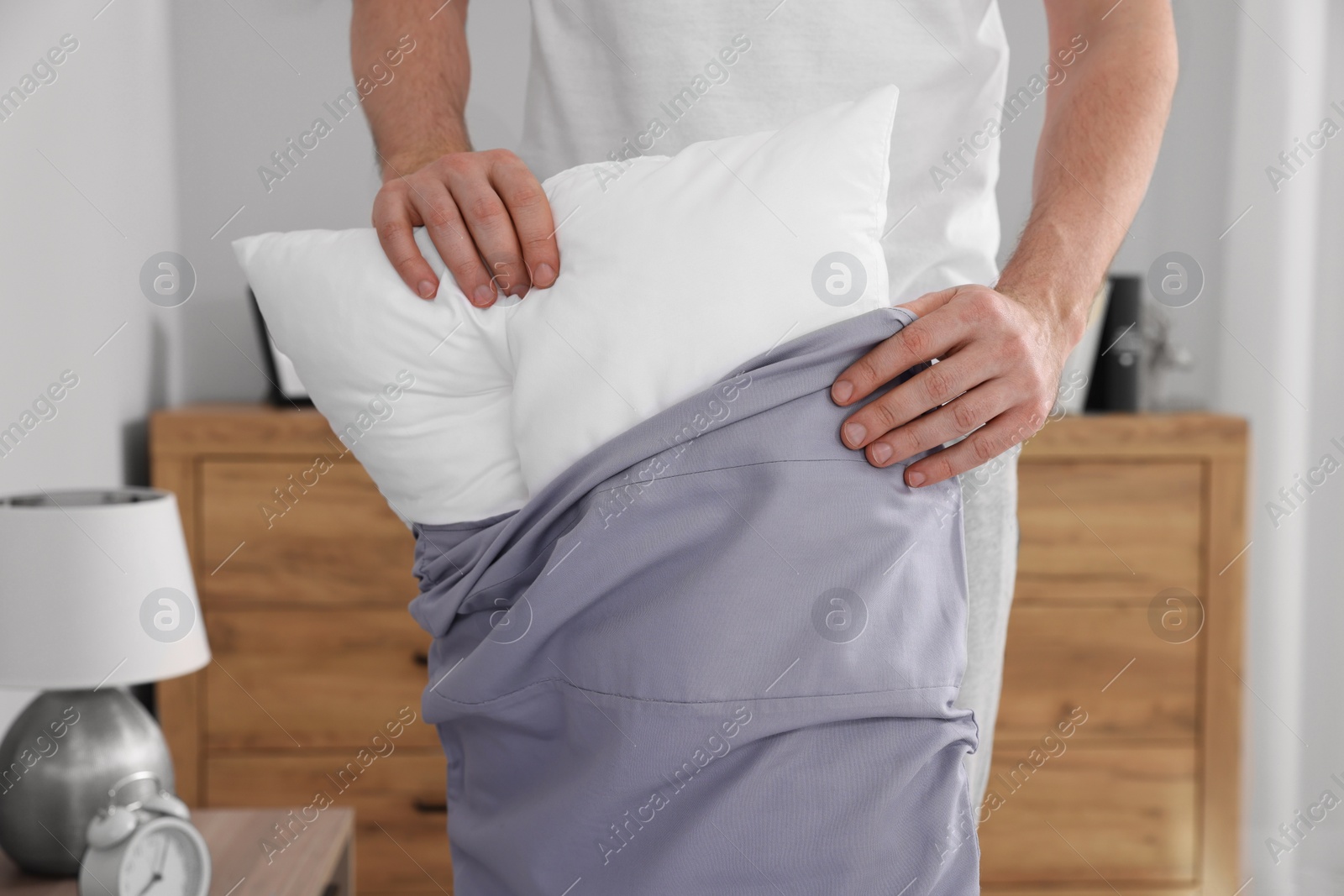 Photo of Man changing pillowcase at home, closeup. Domestic chores