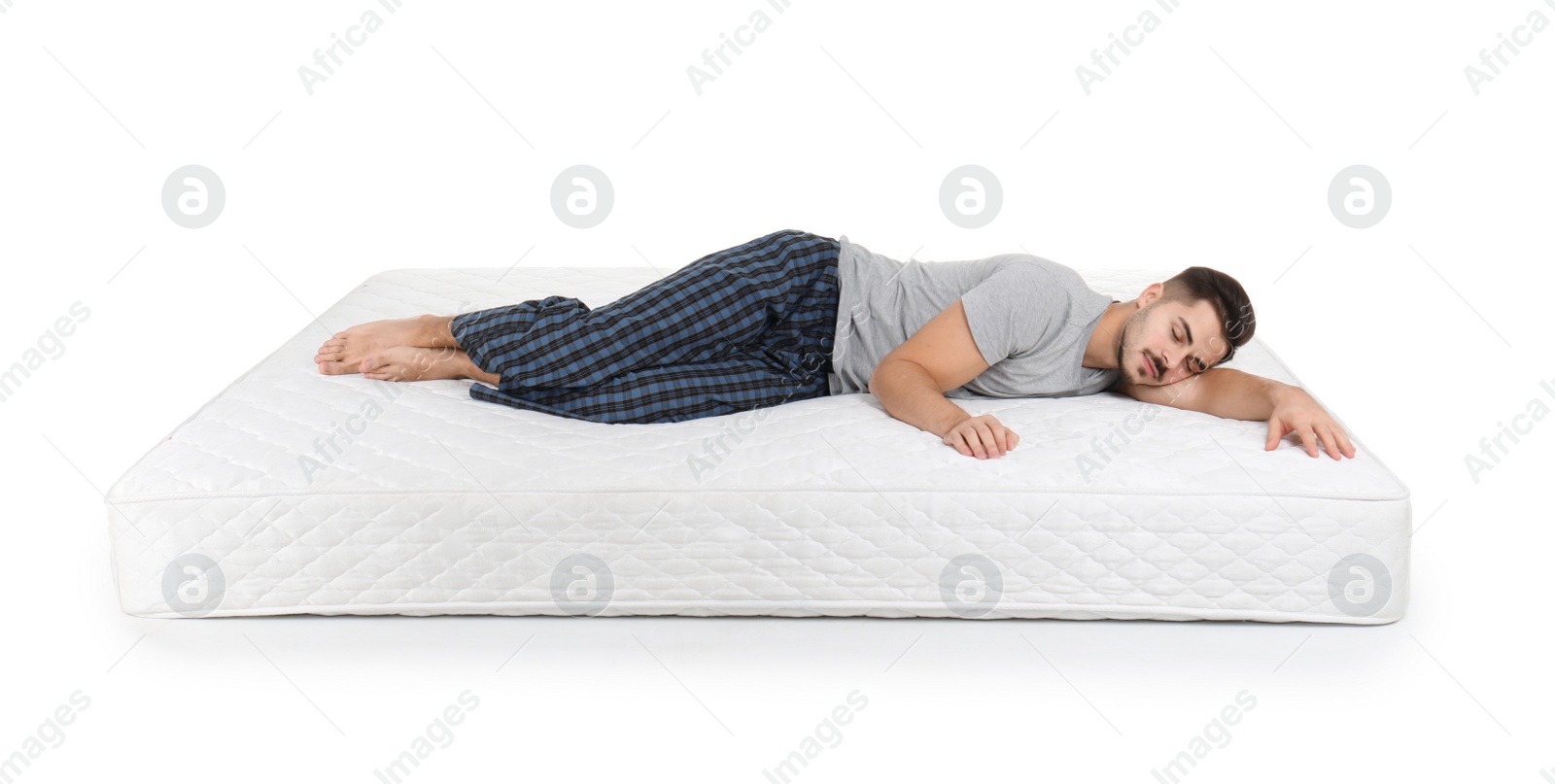 Photo of Young man lying on mattress against white background