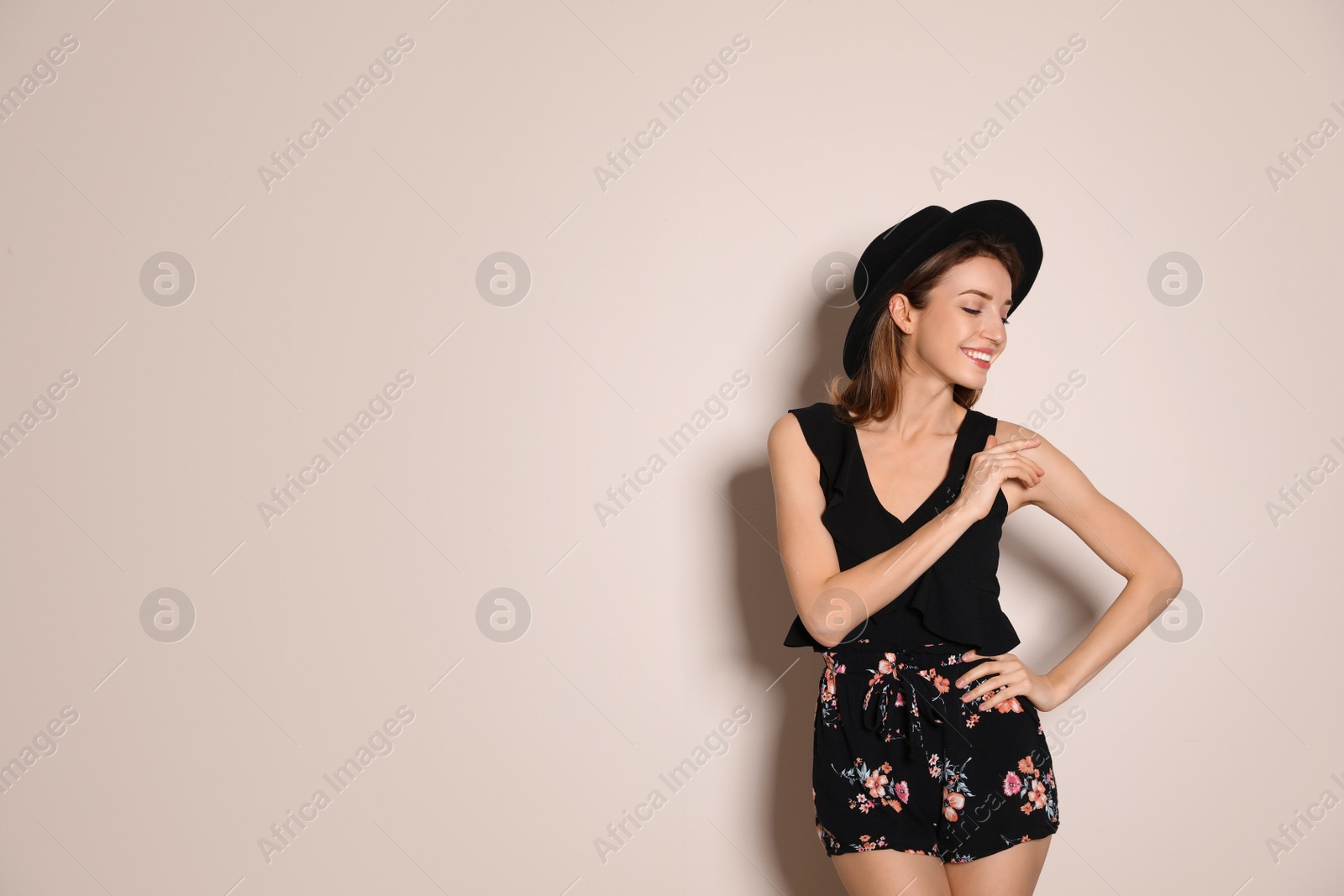 Photo of Young woman wearing floral print shorts and stylish hat on beige background. Space for text