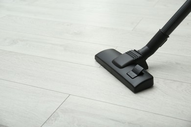 Photo of Hoovering floor with modern vacuum cleaner. Space for text