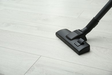 Hoovering floor with modern vacuum cleaner. Space for text