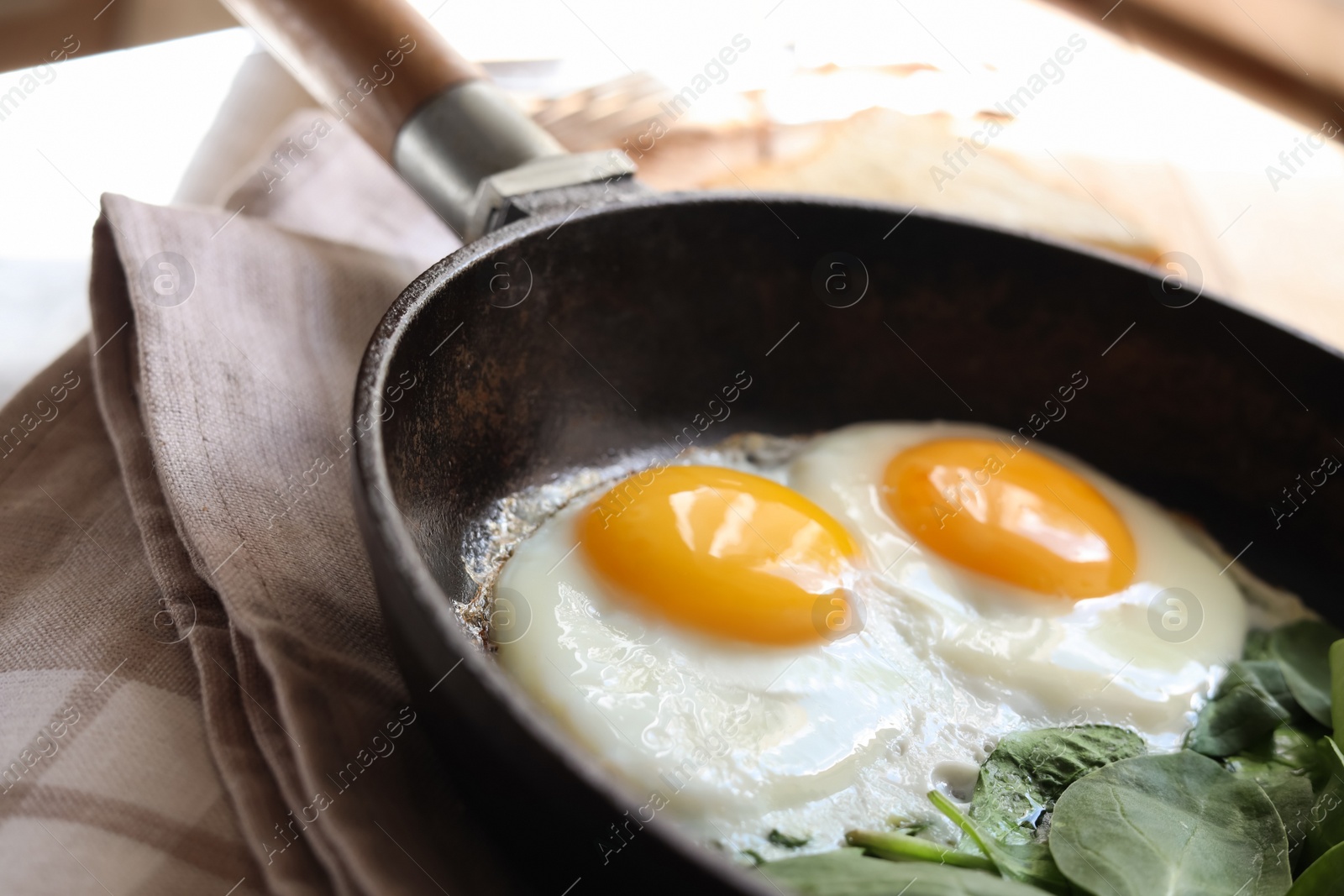Photo of Delicious fried egg with spinach served on wooden table, closeup
