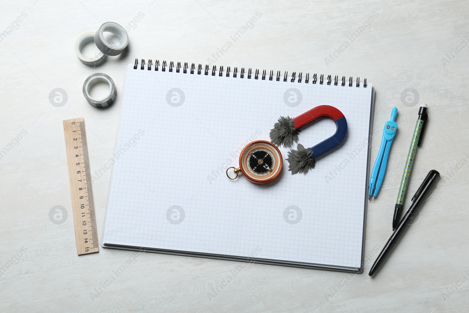 Photo of Notebook, compass and magnet with iron powder on table, flat lay composition. Space for text