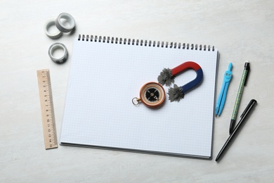 Photo of Notebook, compass and magnet with iron powder on table, flat lay composition. Space for text