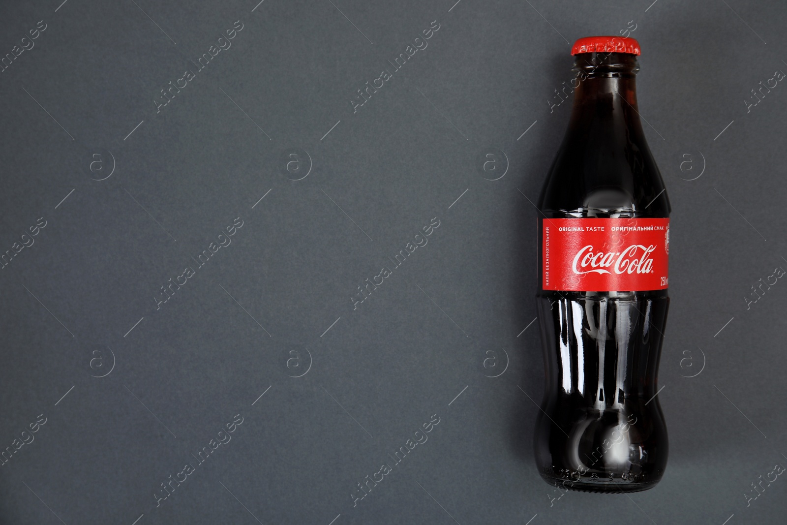 Photo of MYKOLAIV, UKRAINE - NOVEMBER 14, 2018: Bottle of Coca-Cola on grey background, top view. Space for text