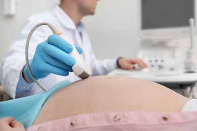Photo of Pregnant woman undergoing ultrasound scan in clinic, closeup
