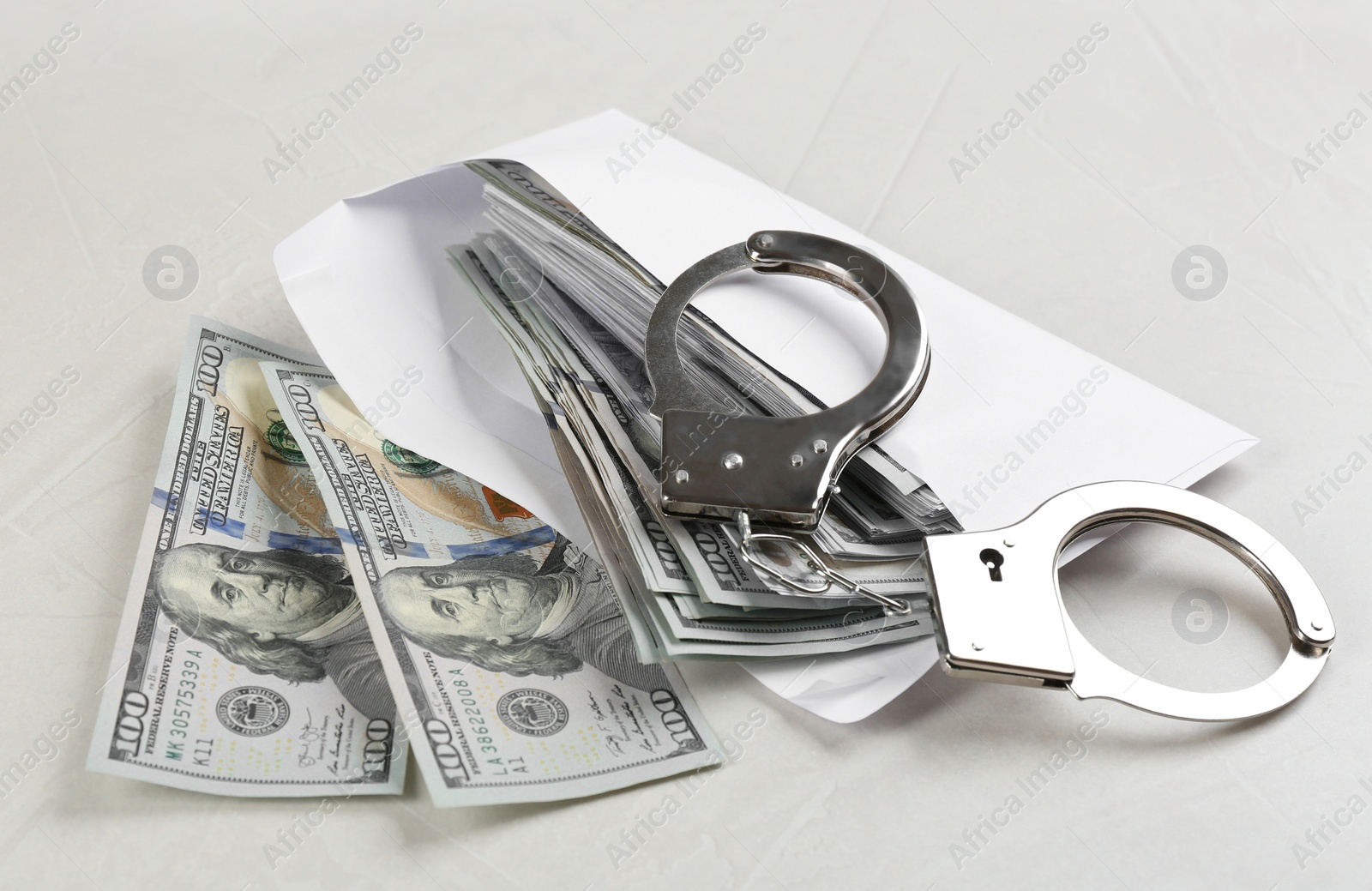 Photo of Dollar bills and handcuffs on light grey stone table. Bribe concept