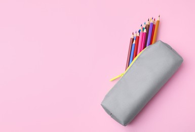 Photo of Many colorful pencils in pencil case on pink background, top view. Space for text