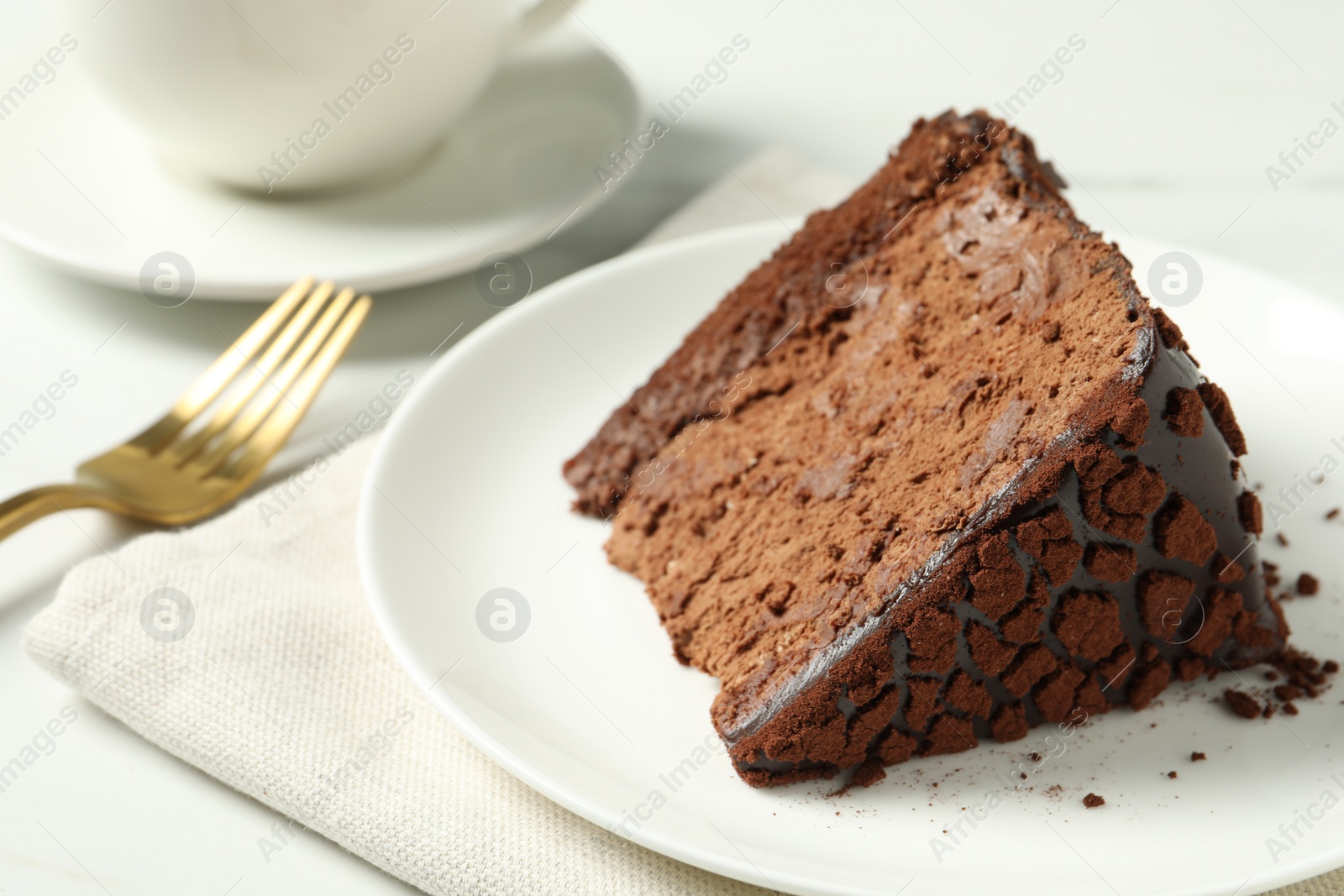 Photo of Piece of delicious chocolate truffle cake on white table, closeup