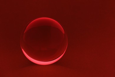 Photo of Transparent glass ball on dark red background