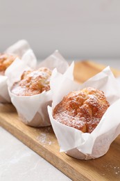 Photo of Delicious muffins with powdered sugar on light table, closeup