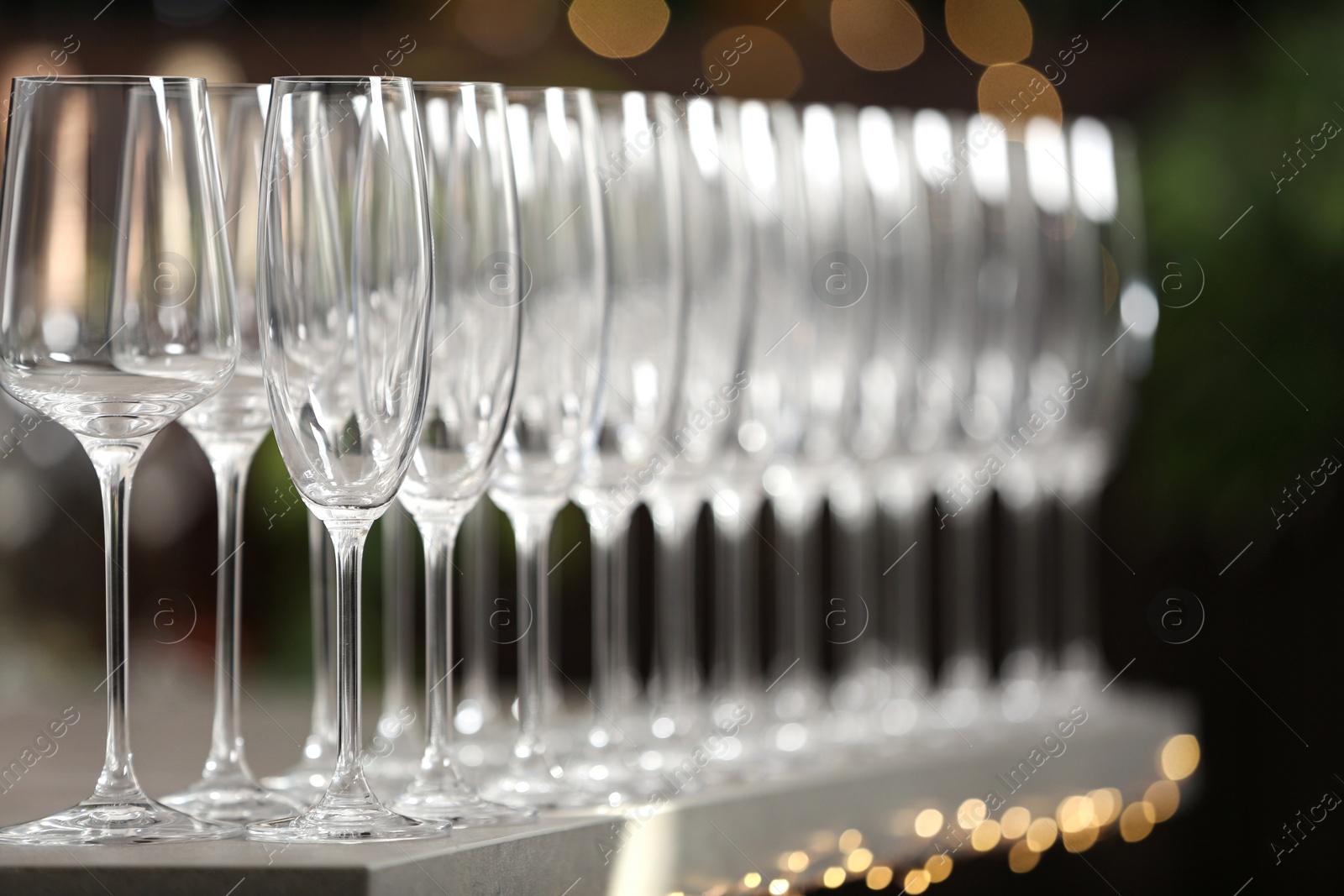 Photo of Set of empty glasses on grey table against blurred background