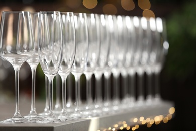 Photo of Set of empty glasses on grey table against blurred background