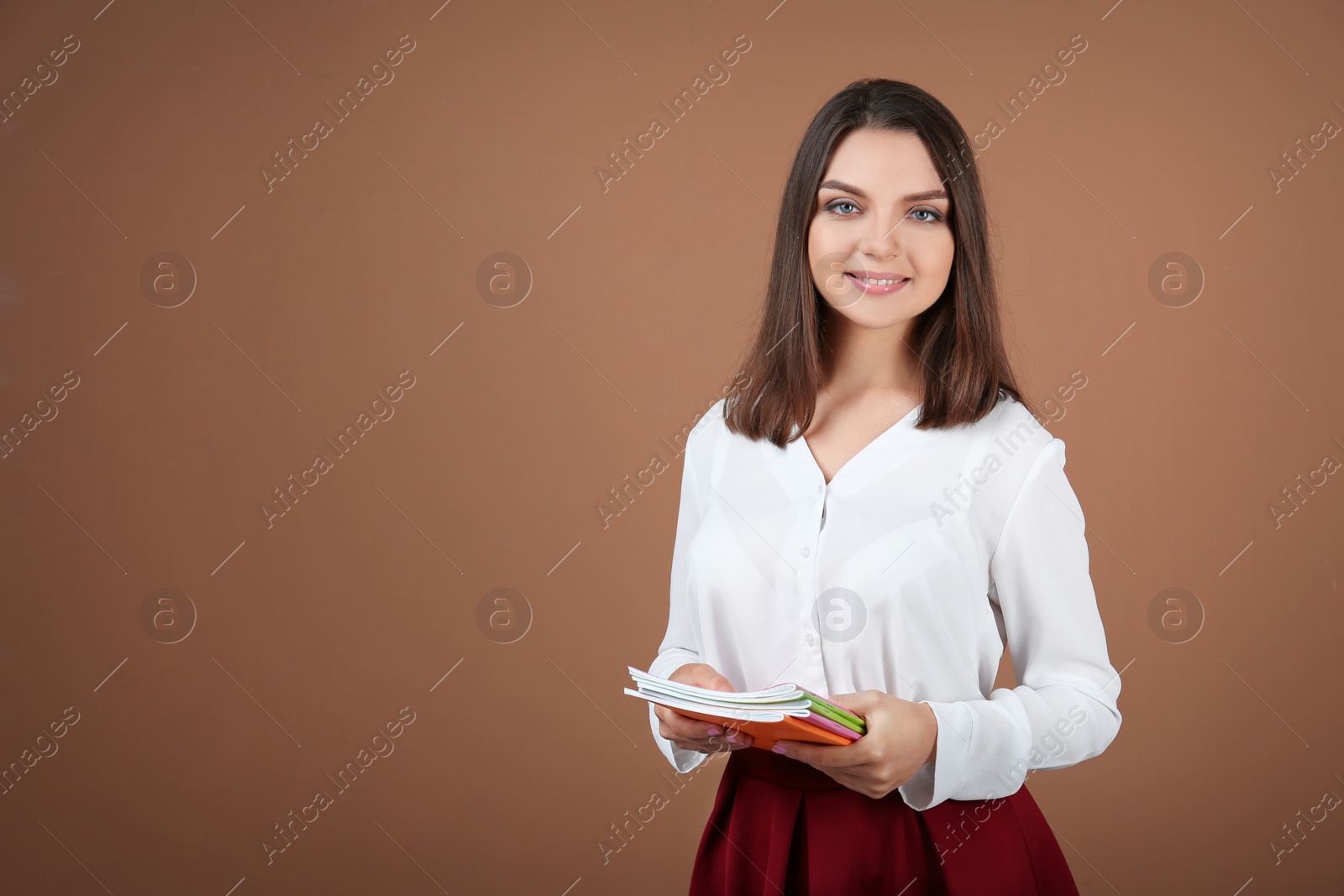 Photo of Portrait of female teacher with notebooks on color background