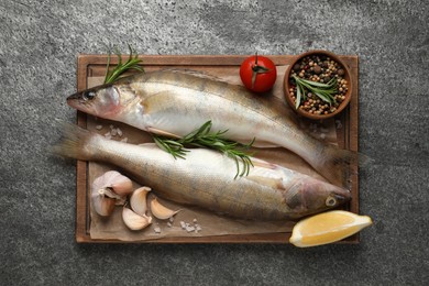 Photo of Fresh raw pike perches and ingredients on grey table, top view. River fish