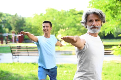 Men practicing morning yoga in sunny park