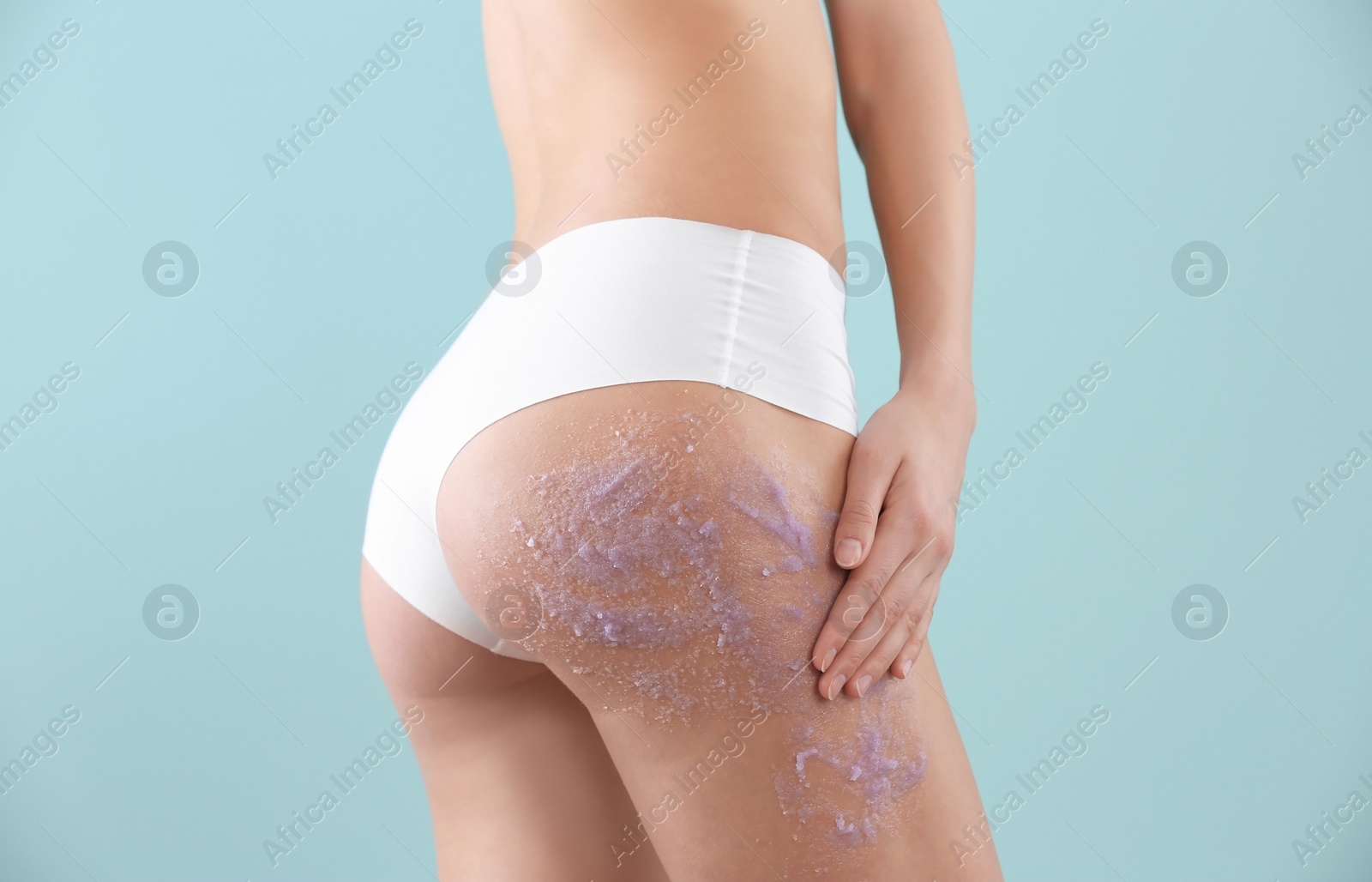 Photo of Young woman applying natural scrub on her body against color background