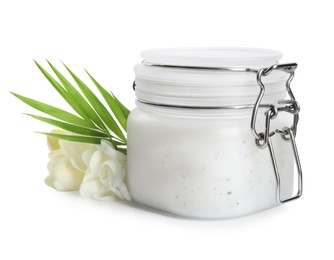 Photo of Jar of exfoliating salt scrub, palm leaf and freesia flowers on white background