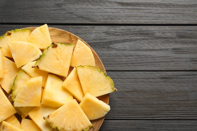 Photo of Plate with fresh sliced pineapple on wooden background