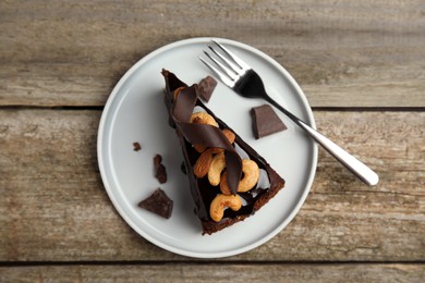 Piece of tasty homemade chocolate cake with nuts on wooden table, top view