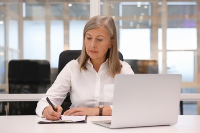 Photo of Confident woman with clipboard and laptop working in office. Lawyer, businesswoman, accountant or manager
