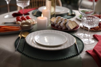 Table setting with burning candles, appetizers and dishware, closeup. Christmas celebration