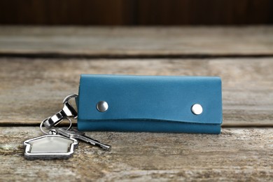 Photo of Leather case with key on old wooden table, closeup