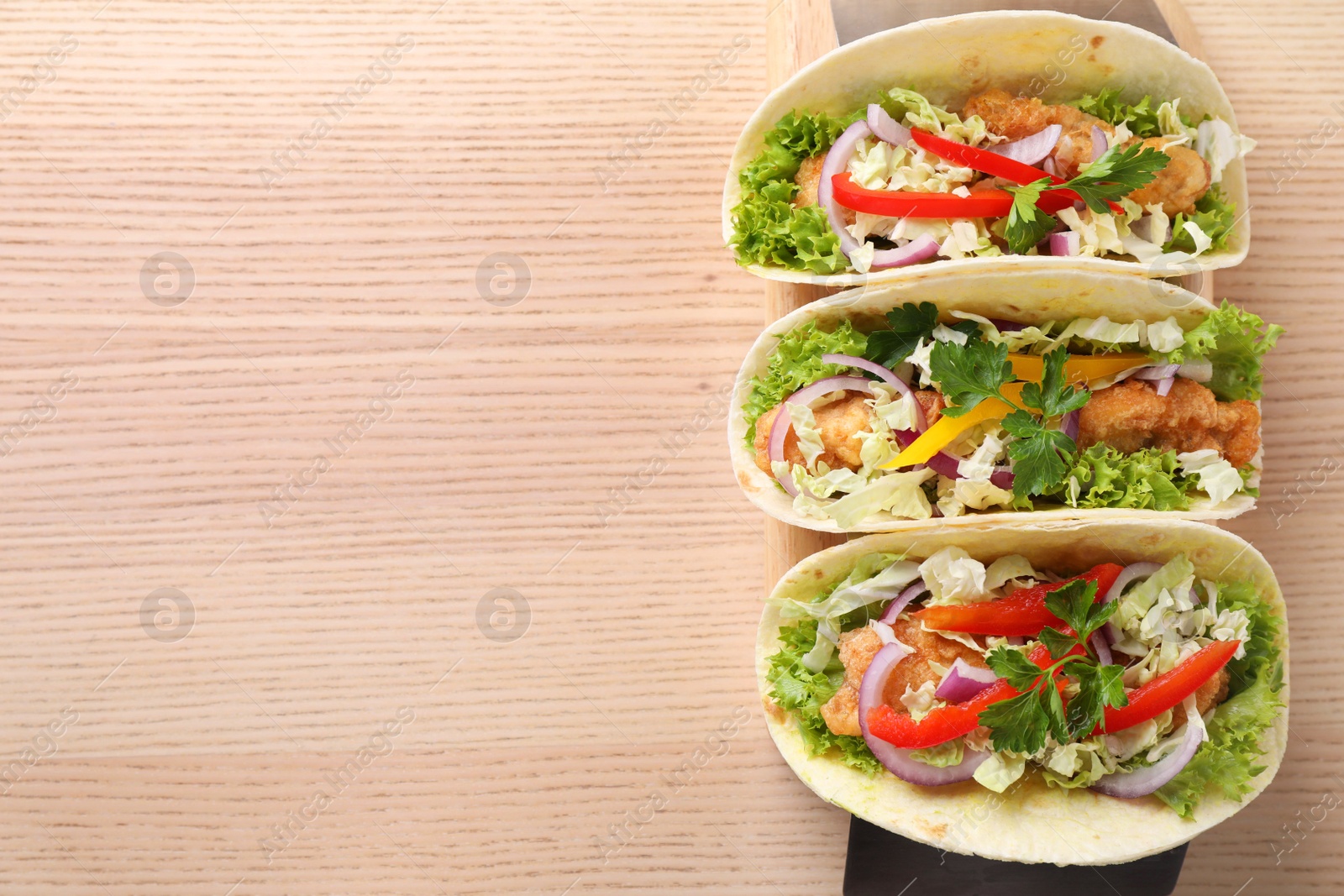 Photo of Delicious fish tacos served on wooden table, top view with space for text