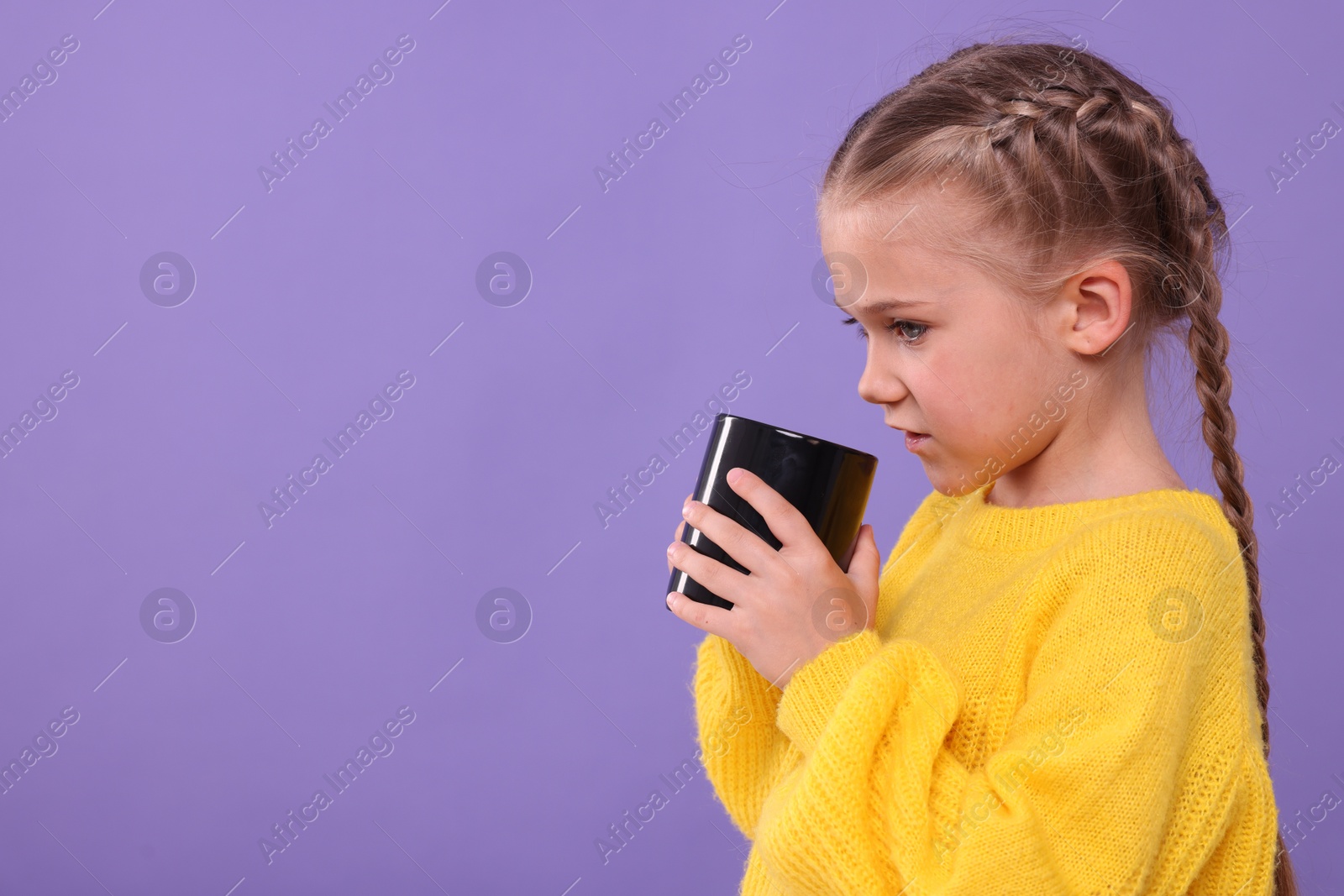 Photo of Cute girl with black ceramic mug on violet background, space for text