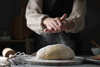 Photo of Making dough. Woman adding flour at grey table, closeup