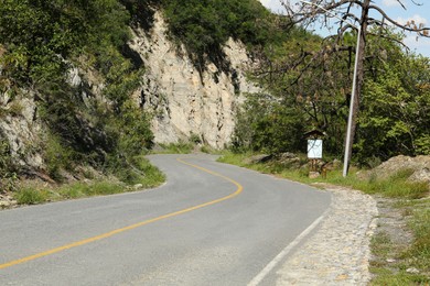 Photo of Empty asphalted road near steep cliff and trees outdoors